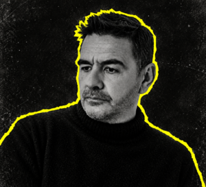 Laurent Garnier in a black turtleneck, pictured in black and white with a yellow outline.