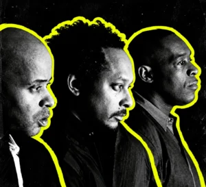 The Belleville Three in a black-and-white group portrait, outlined in bright yellow against a dark background.