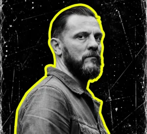 Oscar Mulero with slicked-back hair and beard, in a black-and-white portrait outlined in yellow.