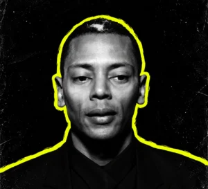 Jeff Mills in a black-and-white portrait with a bright yellow outline on a textured charcoal background.