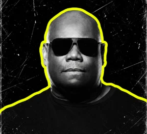 Carl Cox wearing dark sunglasses in a black-and-white portrait with a bright yellow outline.