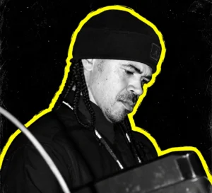 Mad Mike Banks of Underground Resistance at music equipment, in a black-and-white portrait with a yellow outline.