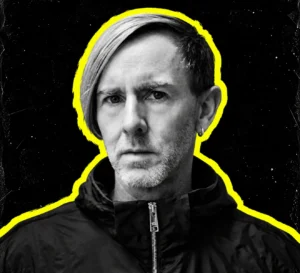 Richie Hawtin with side-swept hair and dark jacket, in a black-and-white portrait outlined in yellow.